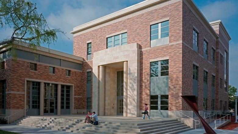 Two students sitting on steps outside the front entrance of Oliphant Hall at Chapman University